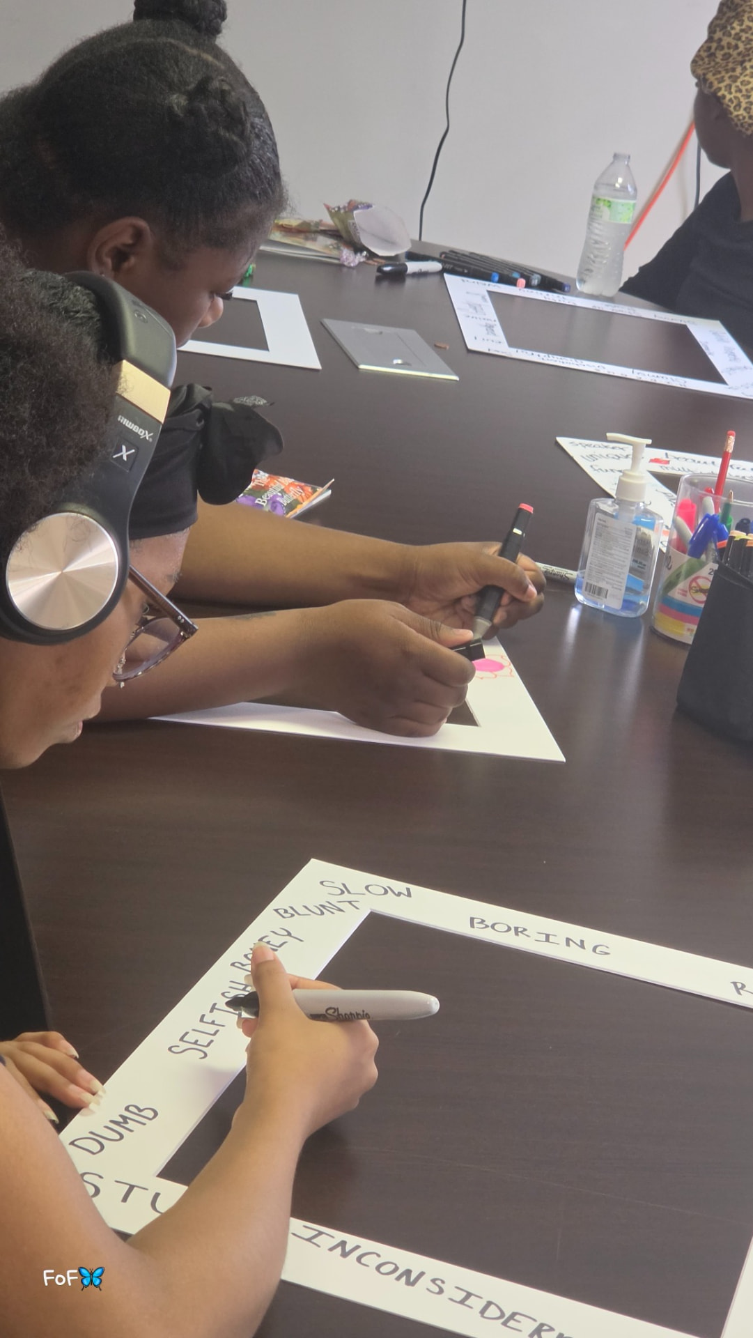 Students seated at a table writing on picture-frame mats during a creative wellness session